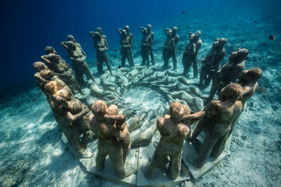 posągi osób stojących w okręgu pod wodą